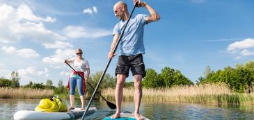 Zwei Personen beim Stand-up Paddling